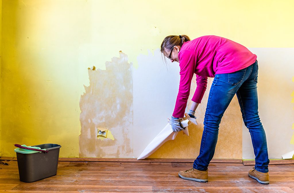 Picture of a woman removing wallpaper.
