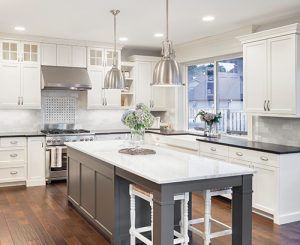 beautiful kitchen in luxury home with island, pendant lights, cabinets, and hardwood floors. tile back splash, stainless steel oven,range, and hood compliment the elegant features
