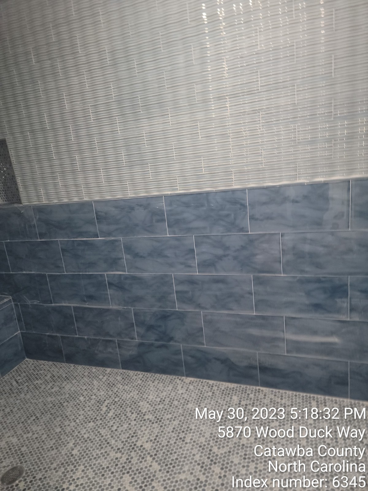 View of shower with blue and white tiles.