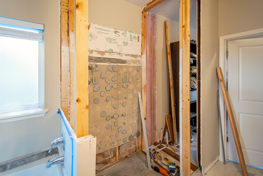 A walk-in shower remodel under construction. Framed with subfloor, curb, drain, cement board, show pan and membrane added before tiling, in a residential bathroom.