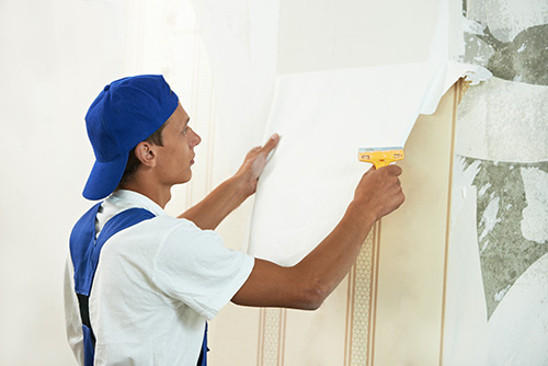 One painter worker peeling off wallpaper during interior residential painting.